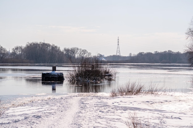 A snowy scene of a river with a boat ramp and a sign that says'the river is frozen '