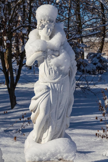 Snowy winter in the city park Snowcovered statue of a woman on a background of snowy trees Smila city Ukraine