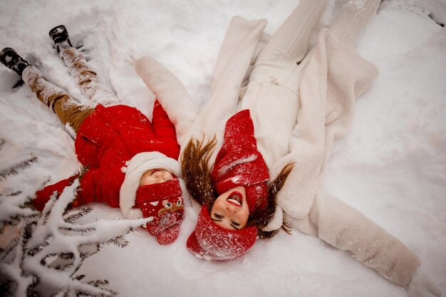 Snowy winter has come mother and son in warm clothes have fun in the snow near the Christmas tree