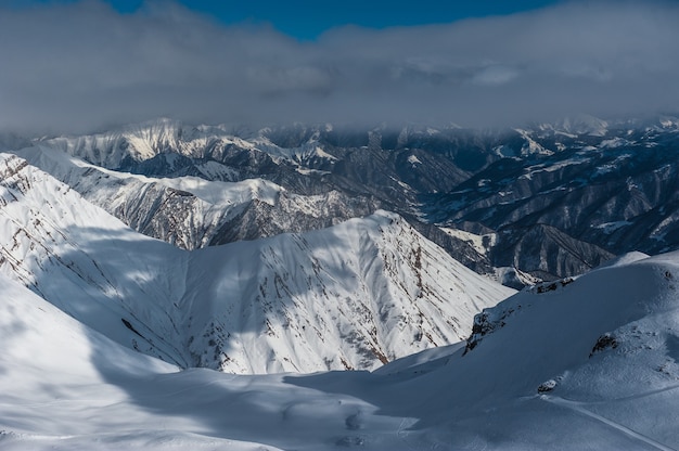 Snowy winter mountains in sun day. Caucasus Mountains, Georgia, from ski resort Gudauri