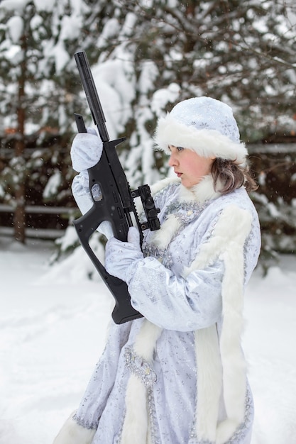 Snowy winter. A young woman in a snow maiden costume holds a rifle.