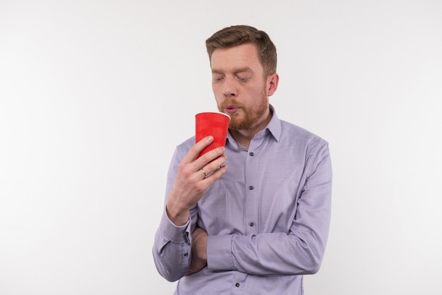 So hot. Nice young man holding a cup of tea while blowing at it