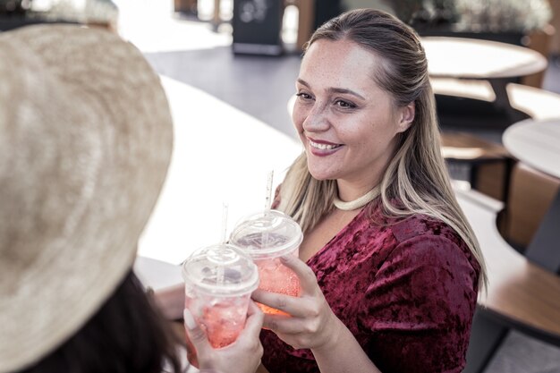 Photo so tasty. delighted happy women smiling to each other while drinking lemonade together