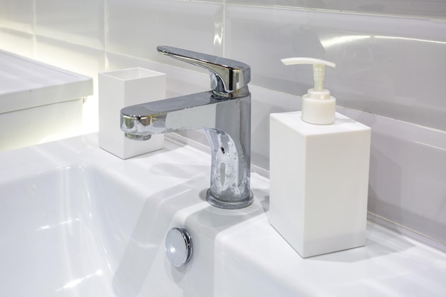 Soap and shampoo dispensers near Ceramic Water tap sink with faucet in expensive loft bathroom