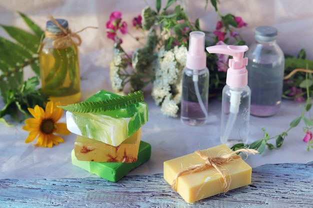 Soap, spray, bouquet of medicinal herbs and glass bottles with aromatic oil on a wooden table