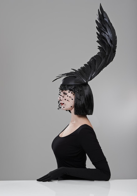 Photo soaring to new heights in fashion shot of a young woman in a wingshaped headpiece sitting in a studio