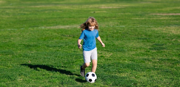 Soccer child play football cute boy kicking soccer ball excited child boy kicking ball in the grass