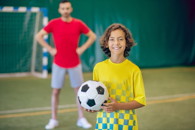 Soccer. Cute boy in yellow uniform feeling good at PE lesson