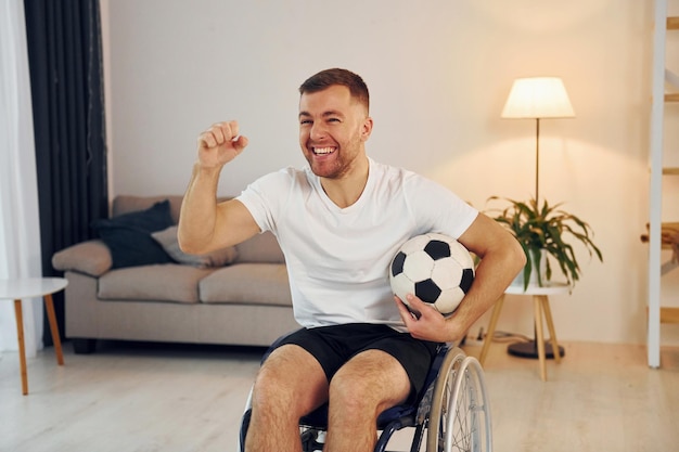 Soccer fan with ball Disabled man in wheelchair is at home