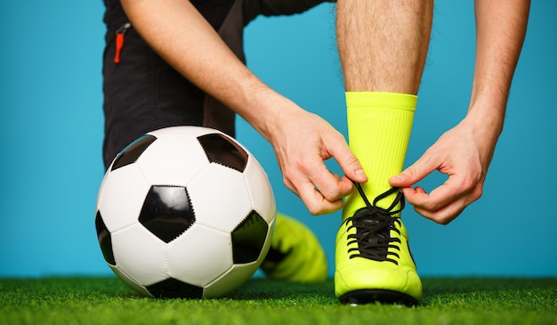 Soccer player getting ready for the game tying his shoes.