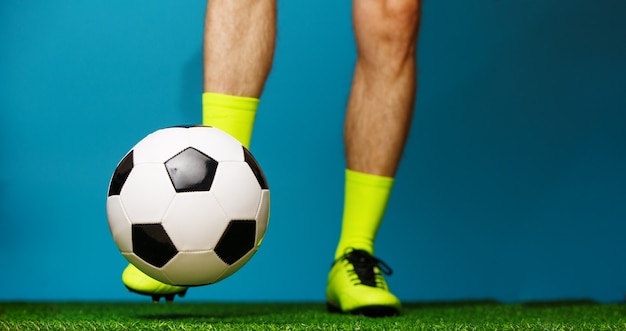 Soccer player with ball on the green grass and blue background