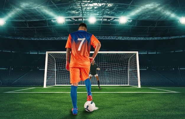 Soccer scene at night match with player in orange uniform kicking the penalty kick