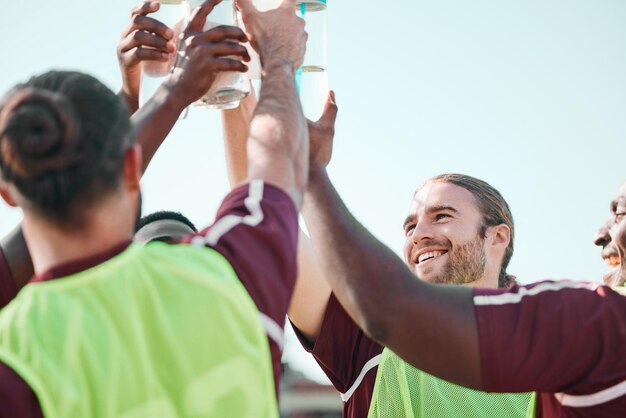 Photo soccer team water bottle and exercise cheers with teamwork achievement and community on grass field fitness workout and sport training of men group with smile and celebration from game with drink