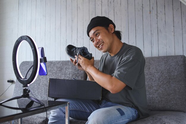 Social media influencer reviewing sport shoe. Smiling Asian man vlogging about sport shoe and filmi