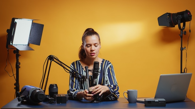 Social media star presenting a fluid tripod head in her professional studio. Influencer making online internet content about video equipment for web subscribers and distribution, digital vlog