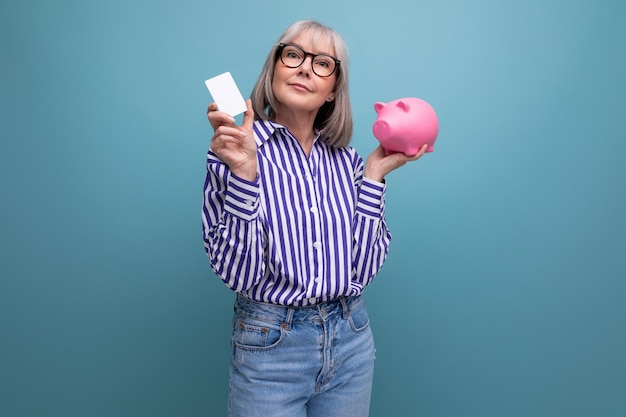 Social protection s middle aged woman with gray hair holding a piggy bank against a bright studio