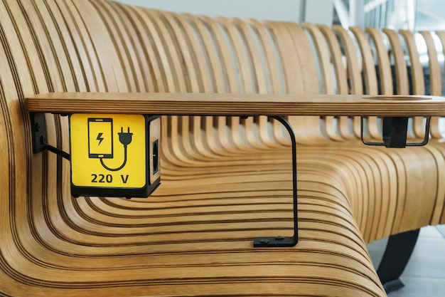 A socket with a device charging sign on a wooden bench at the airport. USB, Wireless, plug