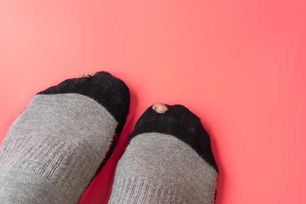 Socks with a hole on a light pink backgroundBroken sock with a hole