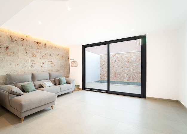 Sofa placed in front of natural stone wall and next to the main window in a living room area