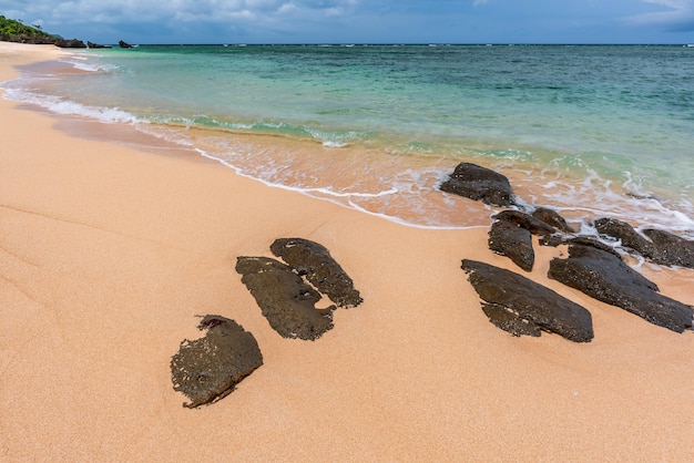 Soft aqua green sea wave over clear sands and amazing rocks on a beach paradise