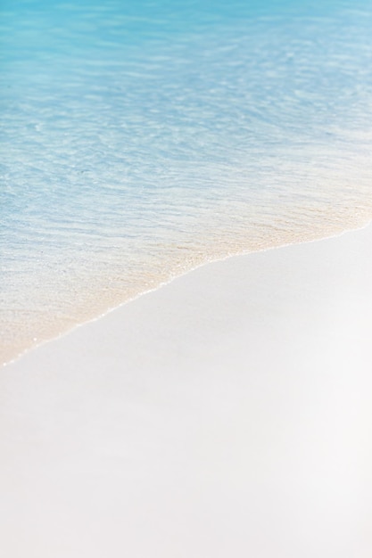 Soft blue ocean wave on clean sandy beach. Ocean wave background. White sand and crystal-blue sea