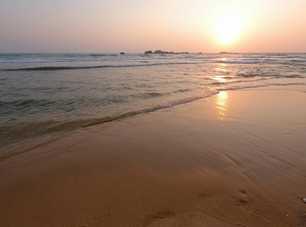 Soft blue ocean waves on a clean sandy beach at sunset