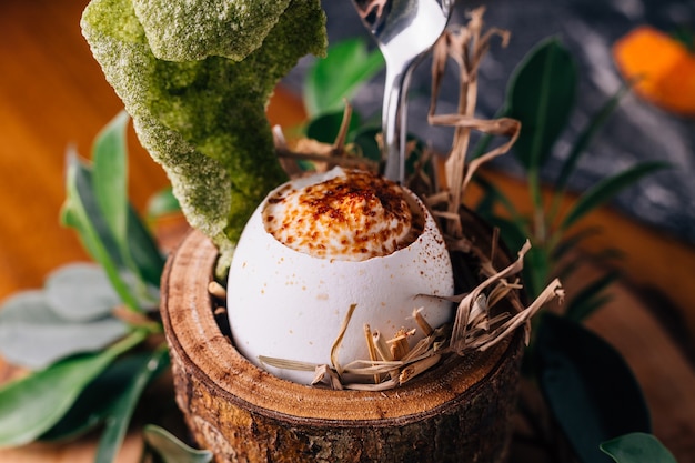 Soft-boiled eggs with shell decorated with small branches, leaves and straw.