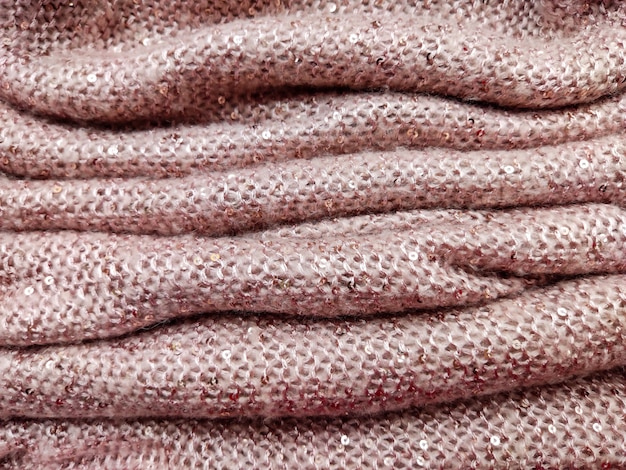 soft fluffy thick woolen fabric of gentle pink color with small sequins sewn into it very warm and cozy texture and textiles rolled and folded into folds