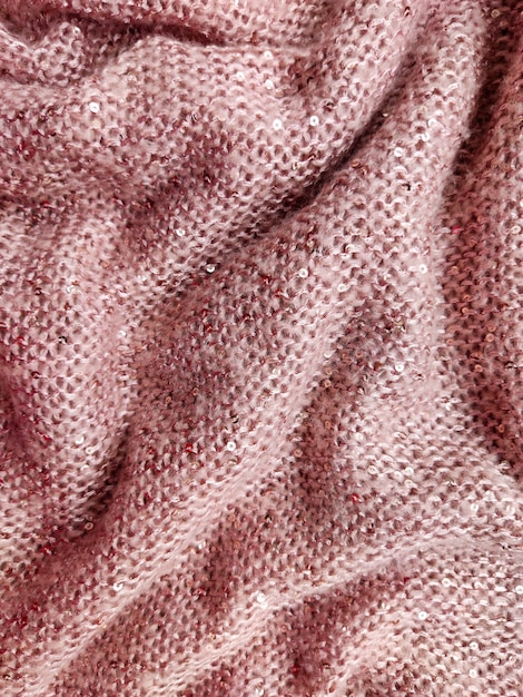 soft fluffy thick woolen fabric of gentle pink color with small sequins sewn into it very warm and cozy texture and textiles rolled and folded into folds