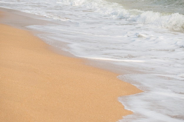 Soft foam wave and sea on the sandy beach background