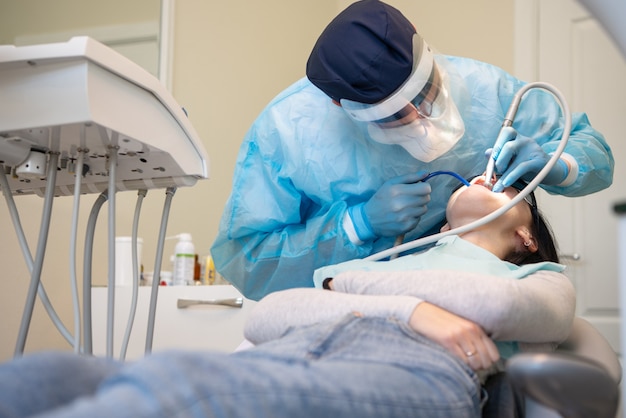 Soft focus of dentist in medical uniform, mask, gloves and lens with patient in a process at clinic.