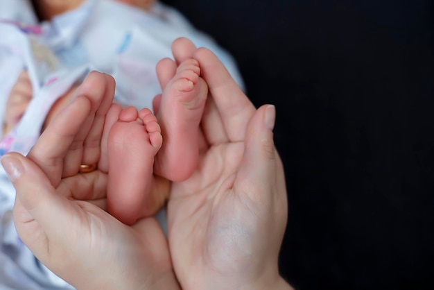 Soft focus Mom holds the little feet of a newborn in her palms