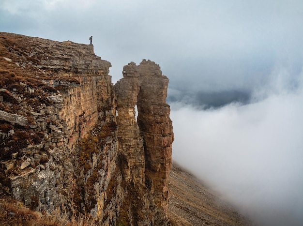 Soft focus Tourist woman stands on the dangerous cliff edge o