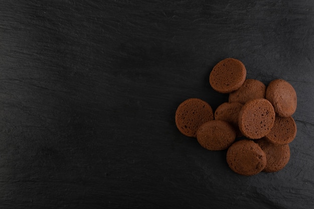 Soft homemade chocolate butter cookies with chocolate filling on black table background. Brown round soft biscuits or fresh sweet cocoa buns