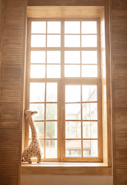 soft plush toy giraffe on a wooden windowsill sunny days children room