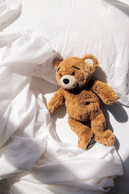 Soft toy bear lies on the bed under natural light Top view flat lay