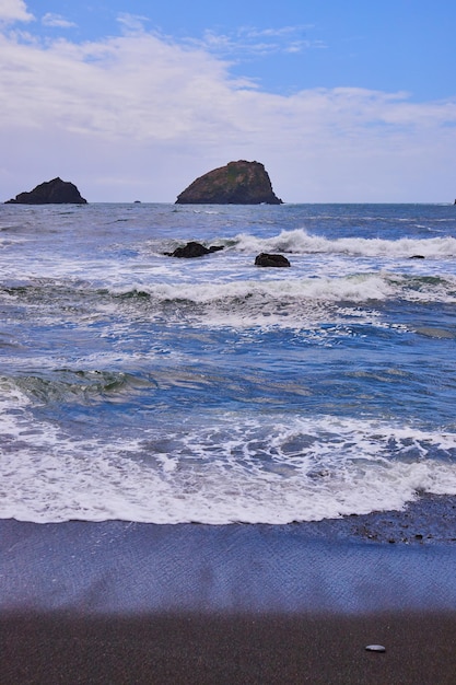 Soft waves hitting black sandy beach on west coast