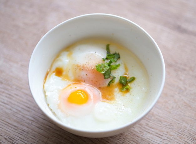 Softboiled eggs on white bowl with pepper coriander on wooden table egg breakfast onsen egg