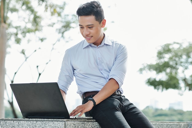 Software developer working on laptop outdoors