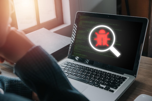 Photo software development and debugging concept person hand using laptop computer with bug software icon on screen software security computer bug failure or error of software