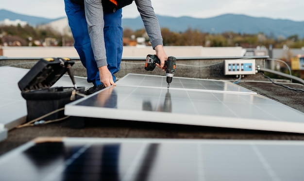 Solar panel technician with drill installing solar panels on roof on family house a sunny day high q