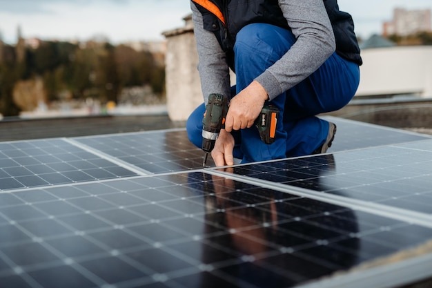 Solar panel technician with drill installing solar panels on roof on family house a sunny day high q