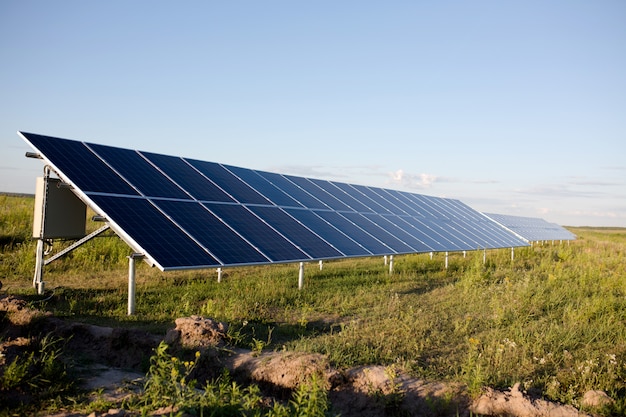 Solar panels, blue sky and green field.