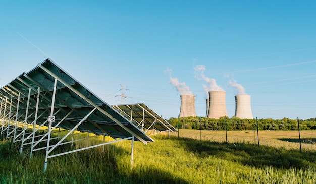 Solar photovoltaics farm and nuclear power plant with cooling towers in background ecology high qual