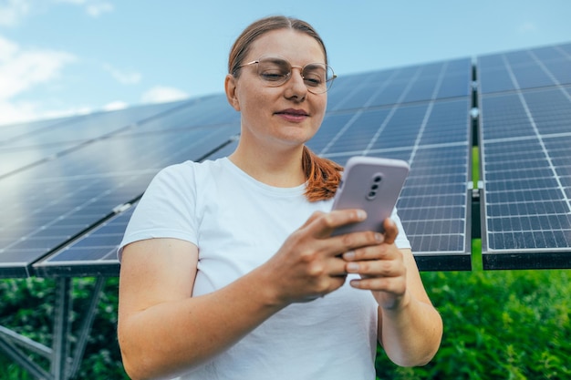 Solar power plant Science solar energy Closeup shot of a young woman with a phone getting acquainted with solar panel on a sunny day green alternative energy concept