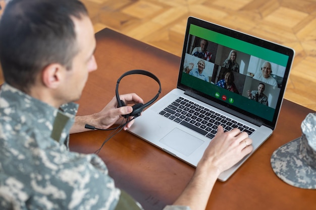 Soldier man smiling while making conference call on laptop indoors