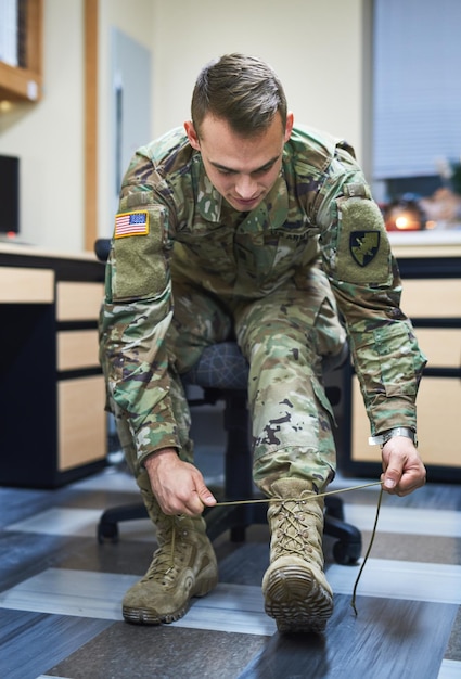 Soldier man and tie shoelaces with boots ready or clothes for Independence Day parade for pride Army officer veteran and camouflage uniform at USA military base march and celebration of freedom