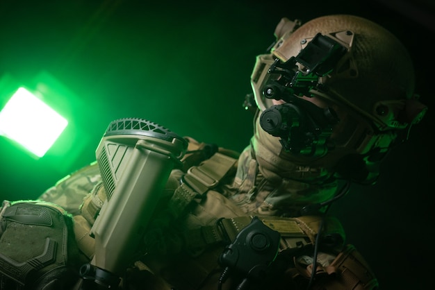 The soldier in military clothing with a night vision device and on a dark background