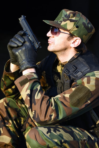 The soldier in uniform is holding the pistol.