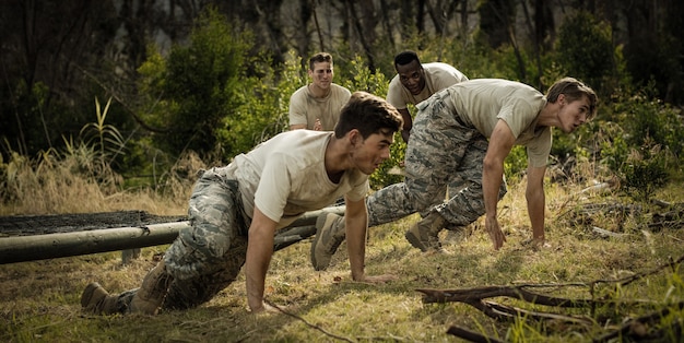 Soldiers crawling under the net during obstacle course